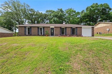 Single story home featuring concrete driveway, brick siding, an attached garage, and a front yard