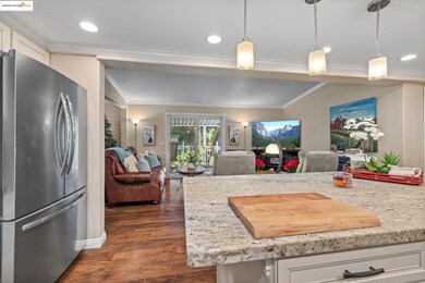 Kitchen featuring freestanding refrigerator, light stone countertops, dark wood finished floors, open floor plan, and pendant lighting