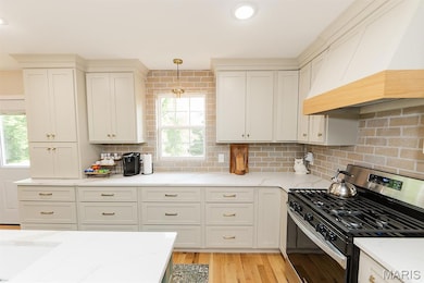 Kitchen featuring gas stove, premium range hood, tasteful backsplash, light stone countertops, and recessed lighting