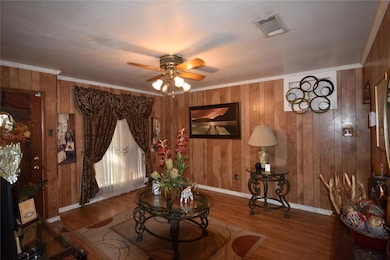 Living room with ornamental molding, wood-type flo