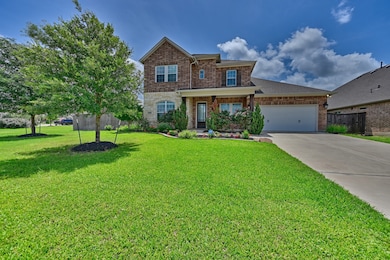 This beautiful two-story brick home features a spacious front yard with well-maintained landscaping. It has a welcoming porch and a large driveway leading to a double garage, perfect for family living.