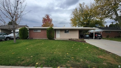 Single story home with brick siding, a front yard, driveway, and an attached carport