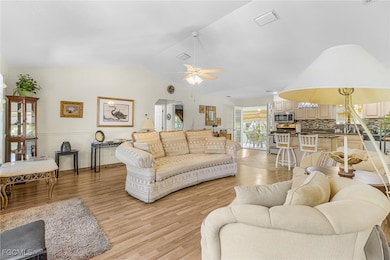 Living room featuring lofted ceiling, a ceiling fan, and light wood-style floors