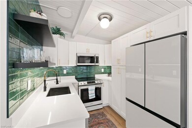 Unit A Kitchen featuring white cabinetry, appliances with stainless steel finishes, light hardwood / wood-style floors, and sink