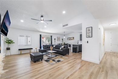 Living area featuring a textured ceiling, light wood-style flooring, ceiling fan, and recessed lighting