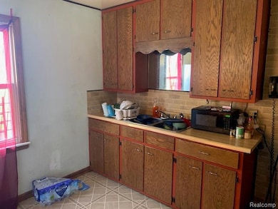 Kitchen featuring light countertops, black microwave, tasteful backsplash, and plenty of natural light