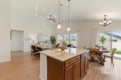 Kitchen with brown cabinets, light wood-type flooring, vaulted ceiling, healthy amount of natural light, and decorative light fixtures