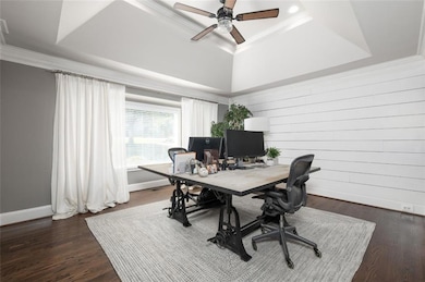 Office featuring a tray ceiling, crown molding, dark wood-type flooring, and ceiling fan