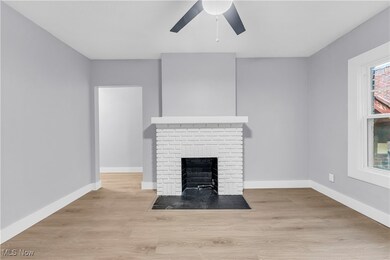 Unfurnished living room featuring light wood finished floors, a brick fireplace, and ceiling fan