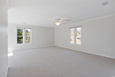 Carpeted empty room with ceiling fan, crown moldin