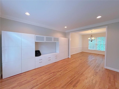 Unfurnished living room featuring ornamental molding, a chandelier, baseboards, light wood-type flooring, and recessed lighting
