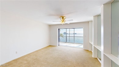 Spare room featuring light colored carpet, a water view, and a ceiling fan