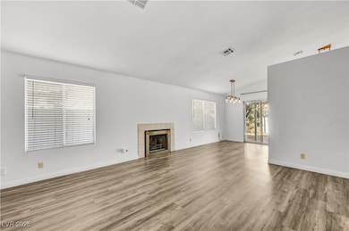 Unfurnished living room with a fireplace, light wood-style floors, and a chandelier