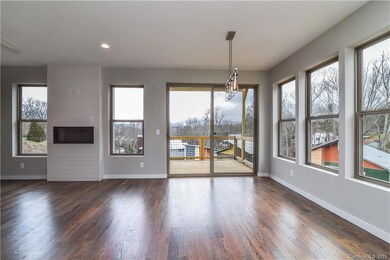 Open concept living and dining rooms with large windows, modern fixtures, hardwood floors