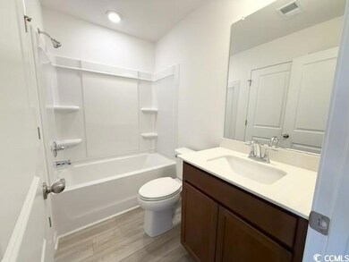 Full bath with washtub / shower combination, vanity, and light wood-style flooring