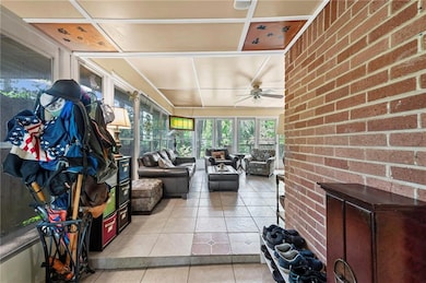 Sunroom featuring a ceiling fan, tile patterned fl