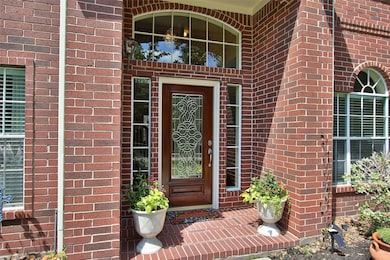 Exterior entry has beveled glass paired with dark cherry wood door framed in large windows.