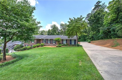 Single story home with a front yard, concrete driveway, and brick siding
