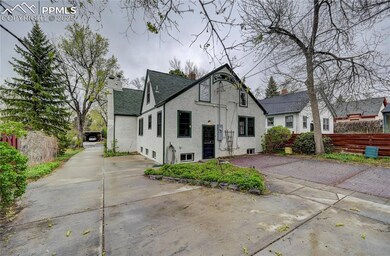 Tudor house with a shingled roof, driveway, a chim