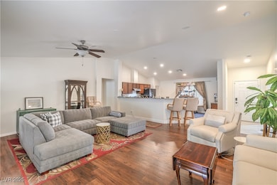 Living area with vaulted ceiling, a ceiling fan, wood finished floors, and recessed lighting