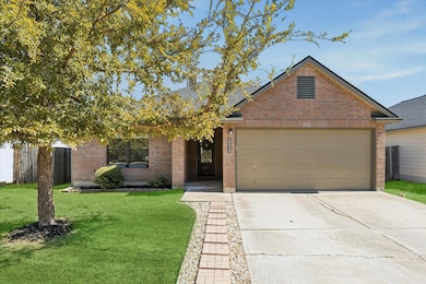 View of front facade featuring brick siding, driveway, a front yard, and an attached garage