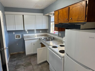 Kitchen featuring white appliances, a textured cei