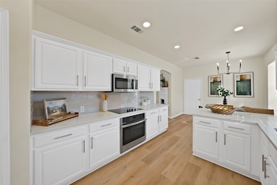Kitchen with white cabinets, backsplash, decorative light fixtures, appliances with stainless steel finishes, and recessed lighting