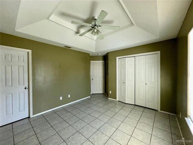 Unfurnished bedroom featuring a tray ceiling, light tile patterned floors, ceiling fan, and a closet