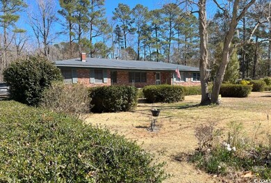 View of front of house with metal roof, brick siding, and a chimney