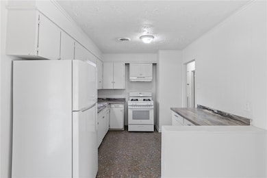 Kitchen featuring white appliances, a textured cei