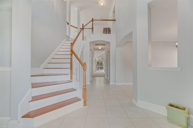 Entrance foyer with a high ceiling, light tile patterned floors, arched walkways, and stairway
