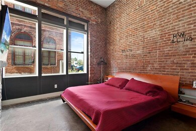 Bedroom featuring brick wall, concrete floors, and