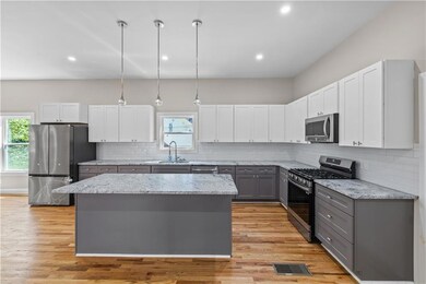 Kitchen featuring gray cabinetry, white cabinetry, pendant lighting, appliances with stainless steel finishes, and tasteful backsplash