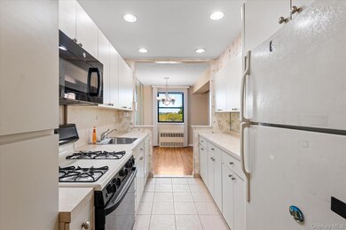 Kitchen featuring white appliances, white cabinetry, light countertops, pendant lighting, and light tile patterned flooring