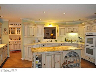 Kitchen. This show stopping kitchen offers a large walk-in pantry, stunning custom cabinets and beautiful tile and granite counter tops.The pass through opens to the den and the full wet bar is in the hall behind the kitchen.
