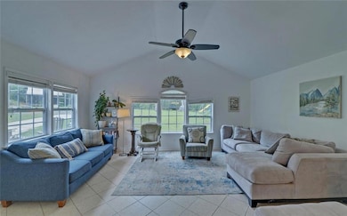 Living area with plenty of natural light, light tile patterned floors, ceiling fan, and high vaulted ceiling