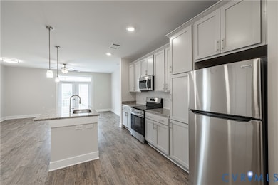 Kitchen with appliances with stainless steel finishes, hanging light fixtures, light stone countertops, dark wood-style floors, and recessed lighting