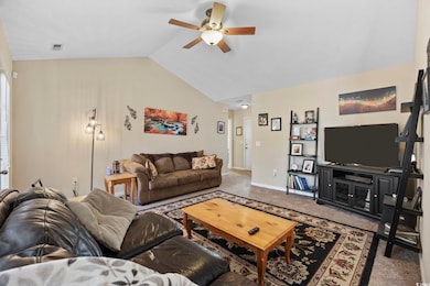 Carpeted living room with lofted ceiling and a ceiling fan