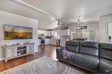 Living room featuring dark wood-style flooring, a ceiling fan, and a chandelier
