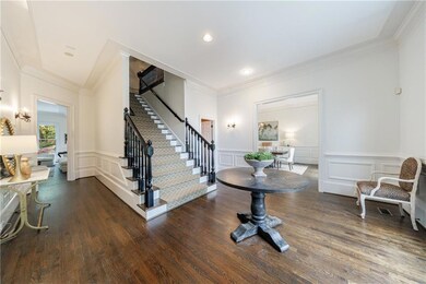 Foyer entrance with a decorative wall, dark wood-style flooring, ornamental molding, and stairway