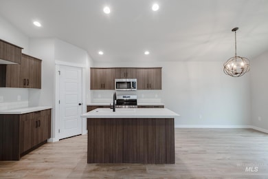 Kitchen with light wood finished floors, a kitchen island with sink, appliances with stainless steel finishes, recessed lighting, and pendant lighting