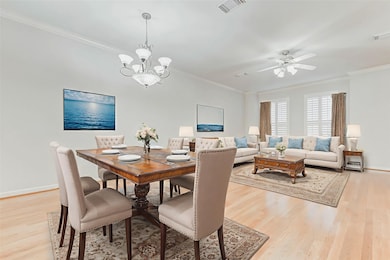 The formal dining area sits just off the living room, defined by a beautiful chandelier and framed by crisp white trim and wide-open wall space—perfect for showcasing art or mirrors. Rich wood floors flow throughout, creating continuity and elegance ideal for dinner parties or casual meals alike. Thoughtful proportions make entertaining effortless.