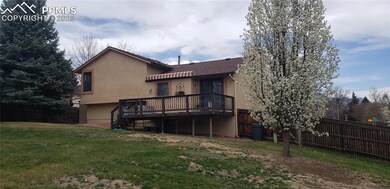 Back of property with stucco siding, stairway, a wooden deck, fence, and a lawn