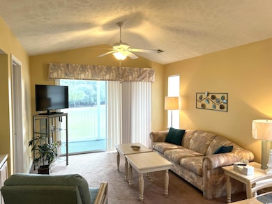 Living room featuring ceiling fan, a textured ceiling, lofted ceiling, and carpet flooring