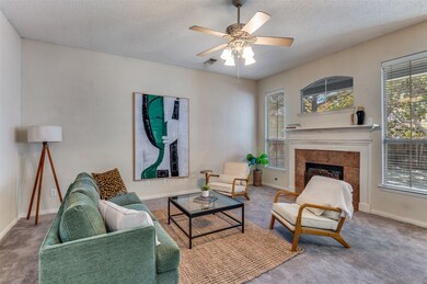 Carpeted living room with a fireplace, a textured ceiling, and ceiling fan