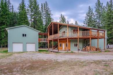 Back of house featuring a deck, stairs, an outdoor structure, view of wooded area, and a garage