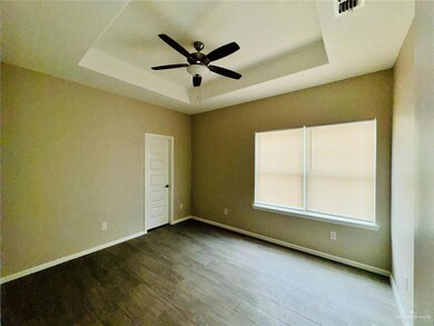 Empty room featuring a tray ceiling, a ceiling fan, and wood finished floors