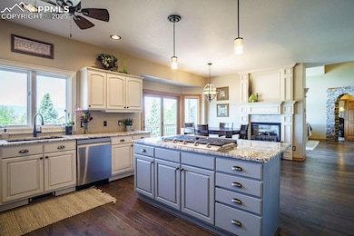Kitchen with stainless steel appliances, a sink, ceiling fan, a multi sided fireplace, and recessed lighting