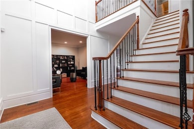 Stairs with a decorative wall and wood finished floors