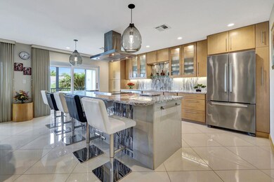Kitchen featuring freestanding refrigerator, island exhaust hood, brown cabinetry, a center island, and recessed lighting
